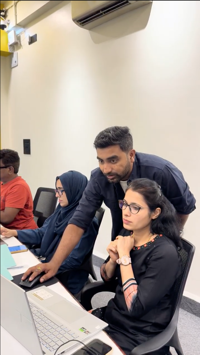 Giriraj leaning over a desk guiding a participant at her laptop